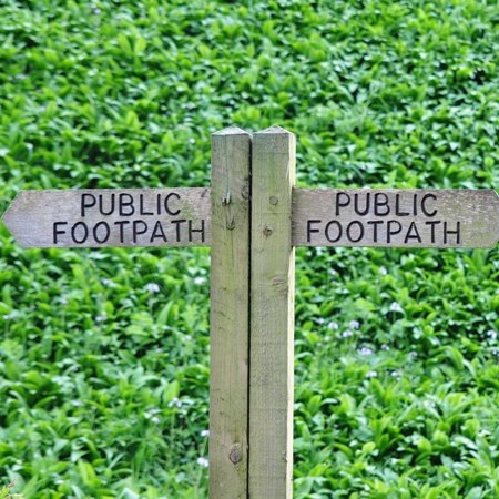 Traditional public footpath signs in green fields on our Cotswold walking trip