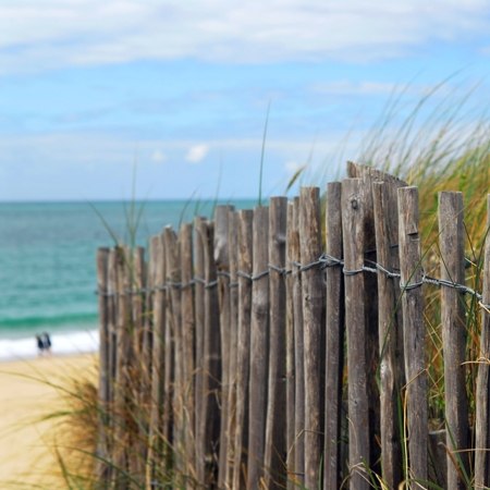 Fenced sand dune leading to a beach and open sea on our French cycling holiday