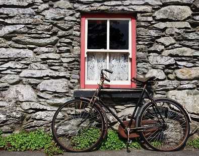 Old bike leaning against stone wall house seen on our Connemara, Ireland cycling holiday