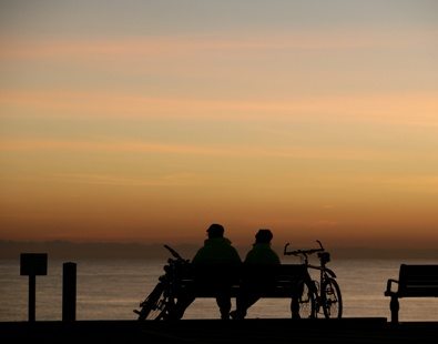 Cyclists rest on a bench and enjoy a beautiful sunset 